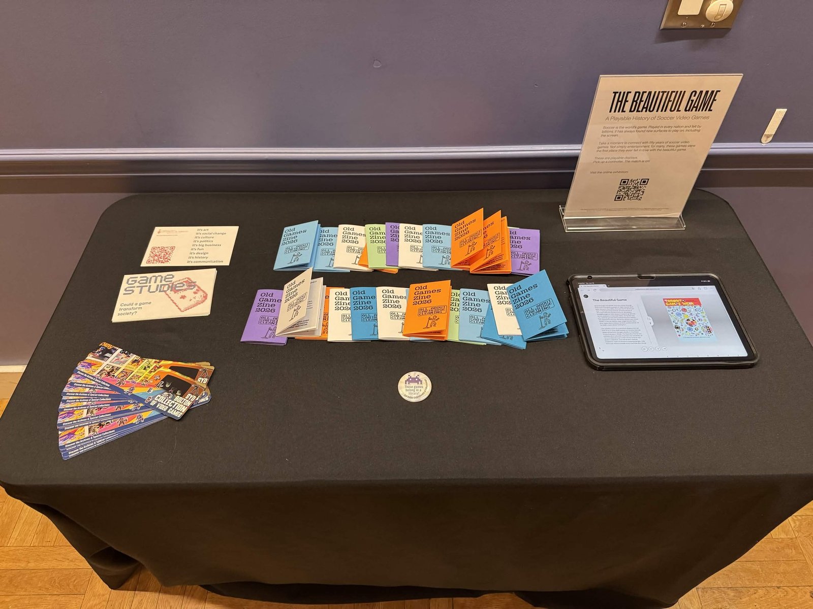 A table with cartridges, the cartridge cleaning zine, and the digital exhibit on a tablet